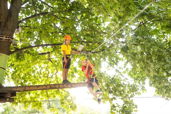 Criança feliz a subir nas árvores. Um parque de cordas. Criança alpinista. Desenvolvimento da primeira infância. Roping Park. Feixe de equilíbrio e pontes de corda. Parque de cordas - centro de escalada — Fotografia de Stock