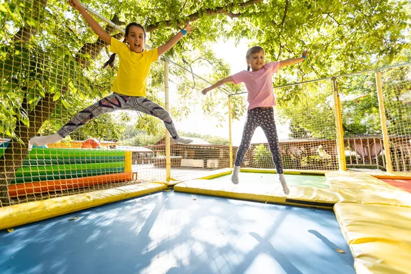 Duas meninas pulando em um trampolim em um dia de verão. — Fotografia de Stock