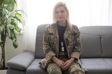 yakın çekim kanepede oturan ve uzağa bakarak TSSB ile askeri üniformalı düşünceli kadın asker portresi