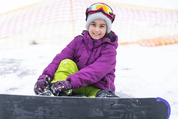 Niña linda aprendiendo a montar una tabla de snowboard para niños, deportes de invierno para el niño, seguridad de los deportes activos. — Foto de Stock