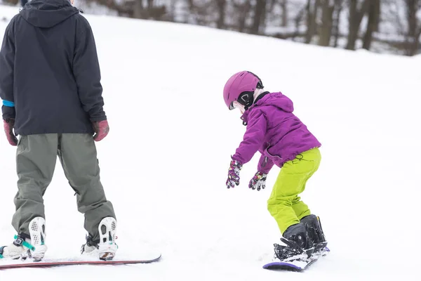 Kis aranyos lány tanul lovagolni egy gyerek snowboard, téli sportok a gyermek, biztonságos aktív sport. — Stock Fotó