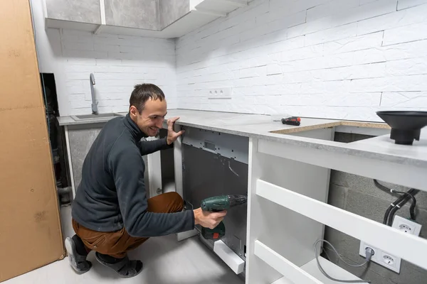 Junge Reparaturkraft repariert Geschirrspüler-Gerät in der Küche. — Stockfoto
