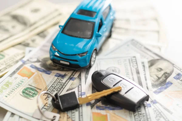 Coche azul del juguete con el dinero y la llave del coche en la mesa de madera . —  Fotos de Stock
