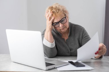 Emekli kadın ev faturalarını hesaplıyor.