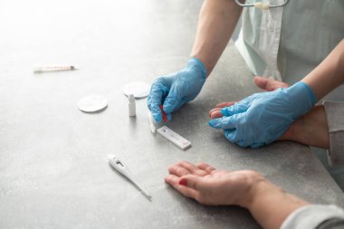 Coronavirus SARS-CoV-2, Covid-19 için antikorlar için COVID-19 testi yapın. Sıhhiyeciler eldiven ile kan testi uygular. Hasta parmaklar, mavi nane arkaplanı