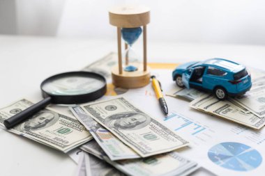 Mavi oyuncak araba ile ahşap masa üzerinde para ve araba anahtar.