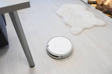 Akıllı Ev. Elektrikli süpürge robotu oturma odasında ahşap zeminde koşar.