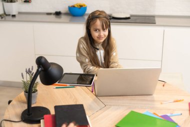 Liseli kız evde dijital tabletle ödevini yapıyor. Çocuk çalışmak için aletler kullanıyor. Çocuklar için eğitim ve uzak mesafe eğitimi. Karantina sırasında evde eğitim. Evde kalıp eğlenin..