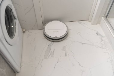 Banyoda beyaz robot elektrikli süpürge.