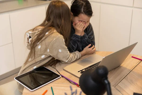 Onlineutbildning. Två skolflickor i hörlurar lyssnar på lektioner på bärbara datorer. Skolan hemma i en pandemi och karantän. — Stockfoto