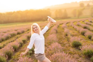 Lavanta tarlasında duran genç bir kadın ve arka planda gün doğumu.