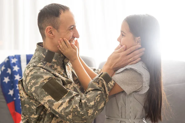 Sotilas, jolla on USA:n lippu ja pieni tytär halaamassa, tilaa tekstille — kuvapankkivalokuva