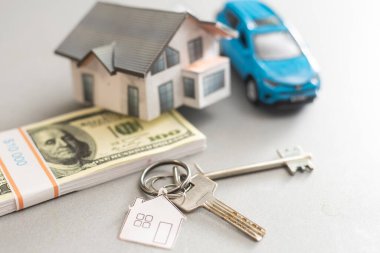 Satılık araba ve ev modeli, parayla birlikte, arka planda anahtar, satılık ev konsepti, yakın plan.