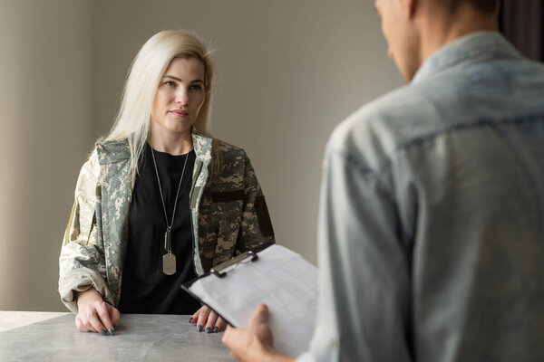 Patriotic military woman. Young patriotic military woman speaking with psychologist making notes