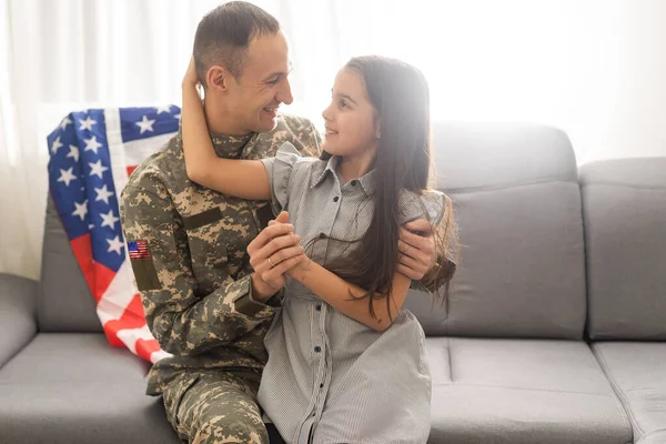 A child girl hugs a military father. dad in military uniform with his daughter. the veterans return to the family — Stock Photo, Image