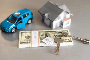 Satılık araba ve ev modeli, parayla birlikte, arka planda anahtar, satılık ev konsepti, yakın plan.