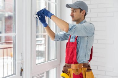 Eldivenli bir işçi yeni plastik kapıdaki kilidi kontrol ediyor.