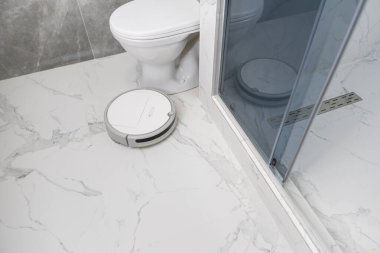 Banyoda beyaz robot elektrikli süpürge.