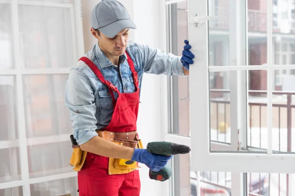 Construction worker installing window in house. Handyman fixing the window with screwdriver — Stock Photo, Image