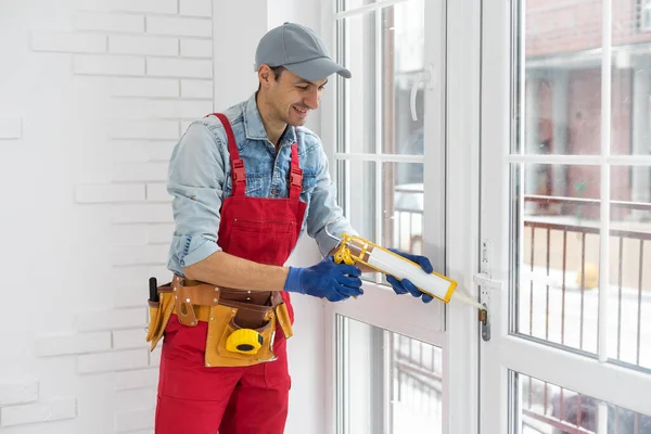 Byggnadsarbetare sätta tätning skumtejp på fönster i hus — Stockfoto