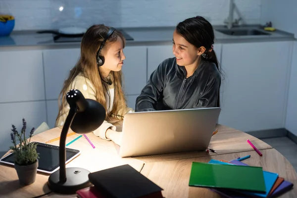 Две девочки-студентки учатся онлайн вместе с учителем по видеосвязи. Братья и сёстры учатся дома с ноутбуком во время карантина из-за пандемии Ковида 19.. — стоковое фото