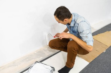 Erkek dekoratör beyaz renkli bir duvar boyuyor..