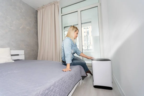 Attractive woman with air purifier on windowsill — Stock Photo, Image