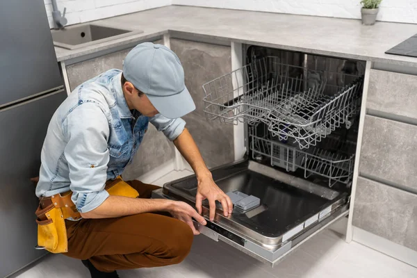 Мужчина открывает или закрывает посудомоечную машину на кухне. — стоковое фото