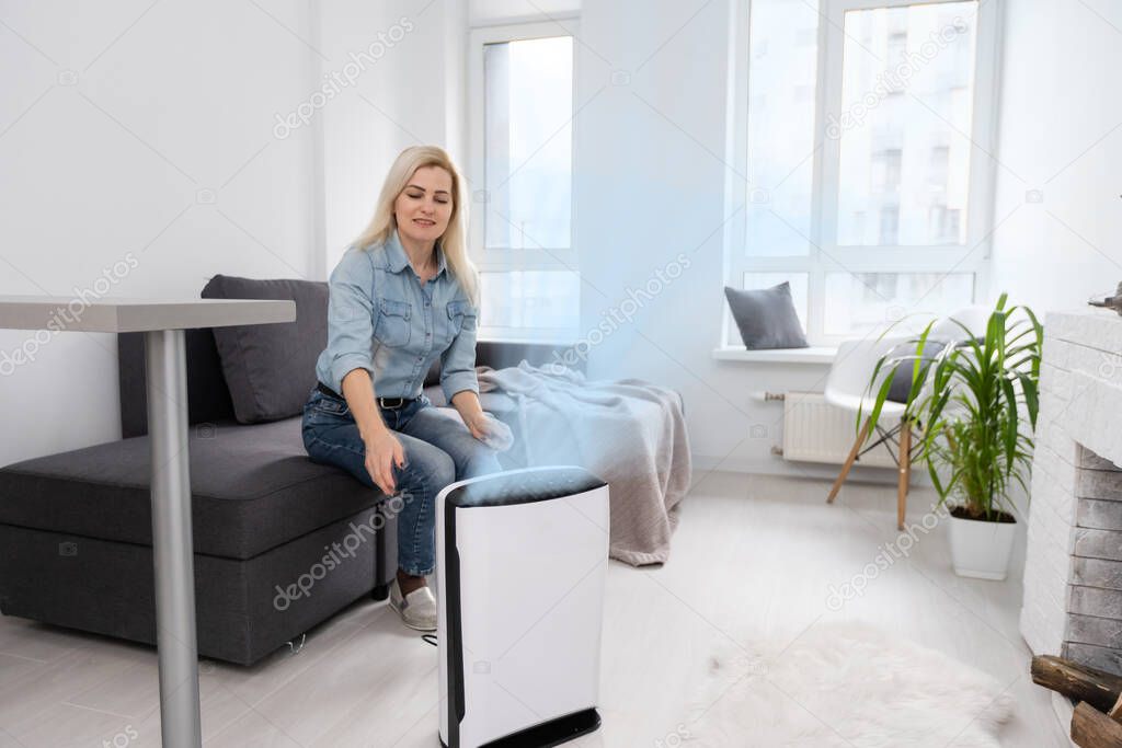 Woman at home in a clean and safe environment from virus by air purifying filter.