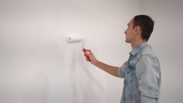 Männlicher Dekorateur bemalt eine Wand mit weißer Farbe. — Stockvideo