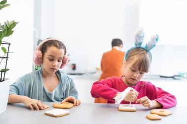 İki tatlı kız kardeş kurabiye yapıp süslüyor.