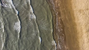 Havadan kumsal manzarası, yaz tatili şablonu afişi. Dalgalar inanılmaz mavi okyanus gölü, deniz kıyısı, kıyı şeridi ile sörf yapar. Mükemmel bir hava aracı üst görüntüsü. Huzurlu, parlak sahil, deniz kenarı.