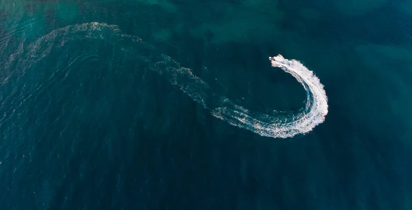 La moto acuática viaja a gran velocidad a través del agua azul, dejando un sendero espumoso. Vista desde arriba — Foto de Stock