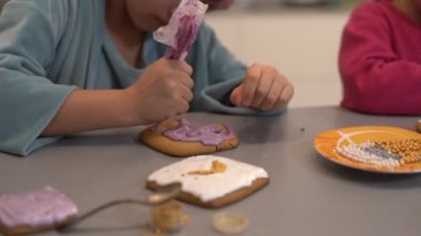 İki güzel kız kardeş, ahşap bir masada lezzetli pastalar süsleyip yiyorlar.