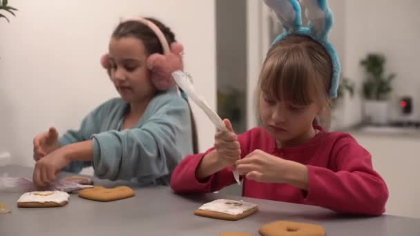Two little sisters decorating homemade cookies in the kitchen at home. — Stock Video
