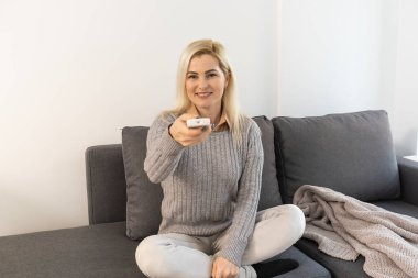 oturma odası holding uzaktan kumandaya rahatlatıcı ve televizyon ya da tv izlerken kadın.