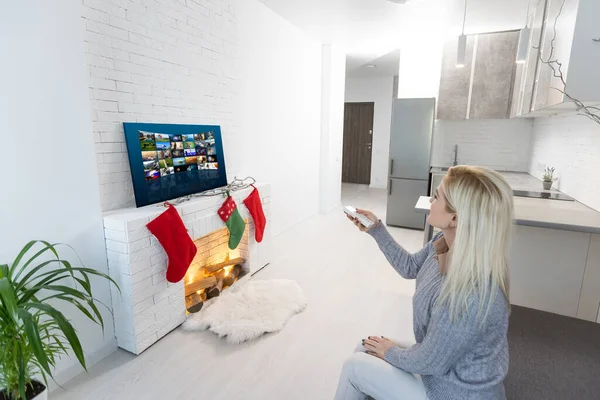 Weihnachten, Winterurlaub und Freizeitkonzept - junge Frau vor dem Fernseher, Kamin zu Hause — Stockfoto