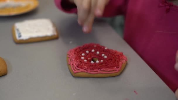 Close up view of kids hands decorating homemade cookies for holidays. A child decorates cookies pressing out fondant or paste from a tube — Stock Video