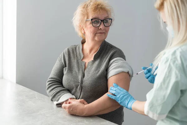 Ιατρός που εμβολιάζει ηλικιωμένο ασθενή στην κλινική με χώρο αντιγραφής. Γιατρός κάνει ένεση σε ηλικιωμένη γυναίκα στο νοσοκομείο. Νοσοκόμα που κρατάει σύριγγα πριν κάνει το εμβόλιο του Covid- 19 ή του Coronavirus. — Φωτογραφία Αρχείου
