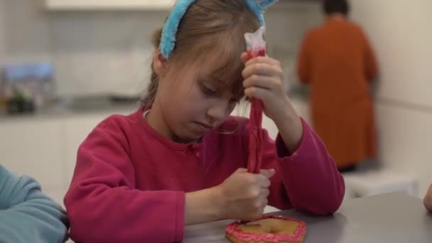 Mädchen schmückt selbst gebackene Lebkuchen zu Ostern — Stockvideo