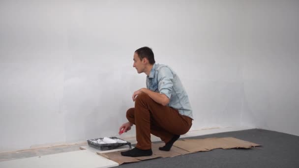 Muž dekoratér malování zeď s bílou barvou. — Stock video