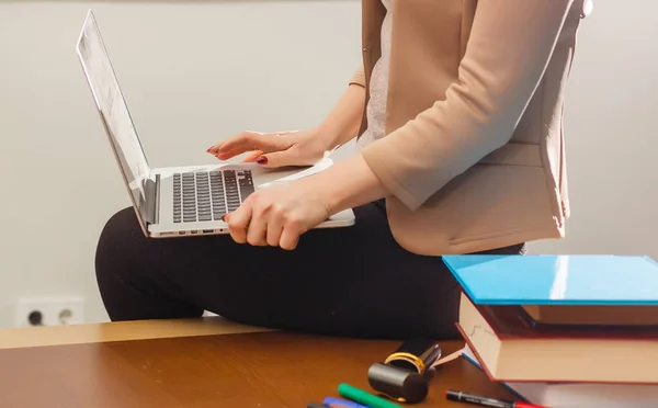 机の上に座ってコンピュータの手で仕事をしている女性 — ストック写真