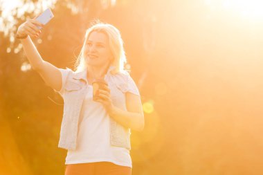 Gülümseyen orta yaşlı bir kadının yaz parkında selfie çekerken görüntüsü