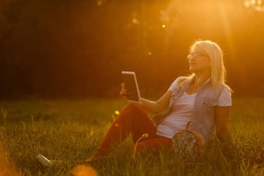 genç kızla mutlu: dijital tablet çim parkta oturan