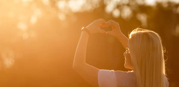 Femme dans la nature tenant symbole en forme de coeur faite avec des mains. — Photo