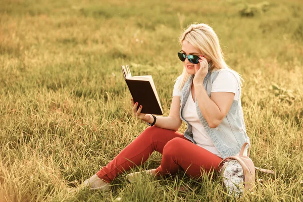 Mulher satisfeita em sentar e ler livro no parque — Fotografia de Stock