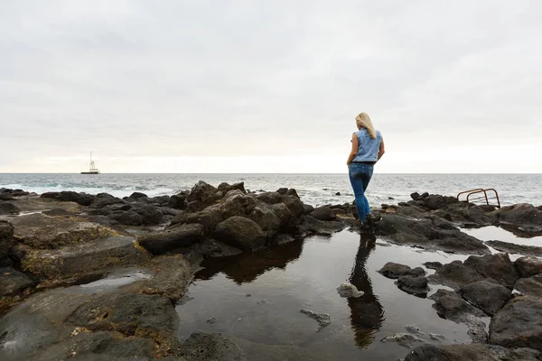 Les femmes sur les roches volcaniques et l'océan bleu avec des vagues, de la mousse blanche et des roches volcaniques. Îles Canaries. La magnifique côte de l'océan Atlantique — Photo