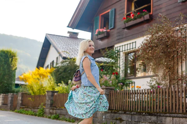 Eine junge Frau steht an Holzhäusern. Dorf in den Bergen. Reisen, Lifestyle-Konzept. Alpen, Europa. — Stockfoto