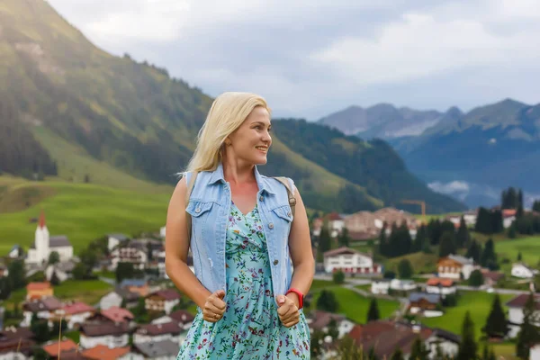 Eine junge Frau steht an Holzhäusern. Dorf in den Bergen. Reisen, Lifestyle-Konzept. Alpen, Europa. — Stockfoto