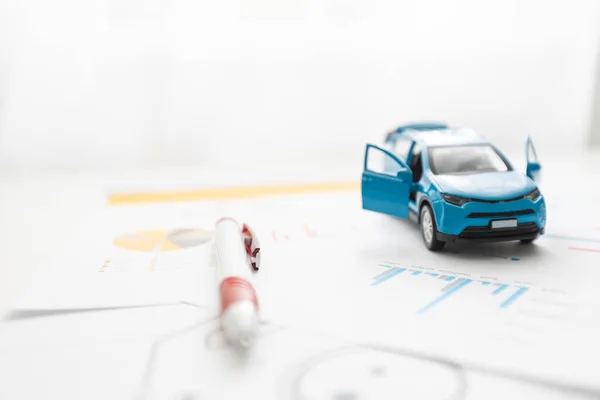 Vooraanzicht van een blauwe speelgoedauto op vellen tekeningen — Stockfoto